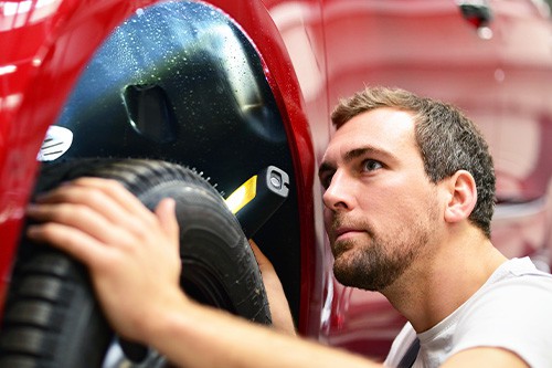 An auto mechanic checking the brakes and tires of a car.