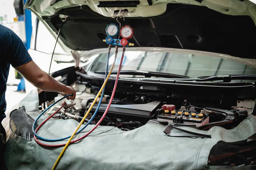 Car AC Repair in Iowa City by Iowa City Tire and Service. Image of opne hood car that is undergoing recharge of air conditioning system service.