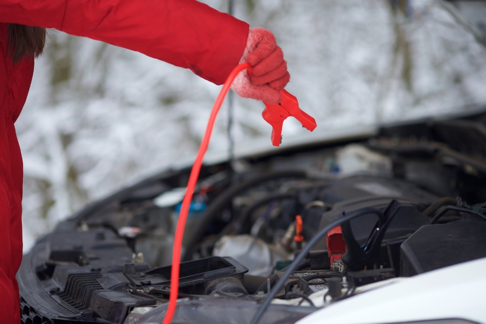 Winter Car Service in Iowa City IA At Iowa City Tire and Service. Car battery being jump-started under open hood during winter due to hard starting issues